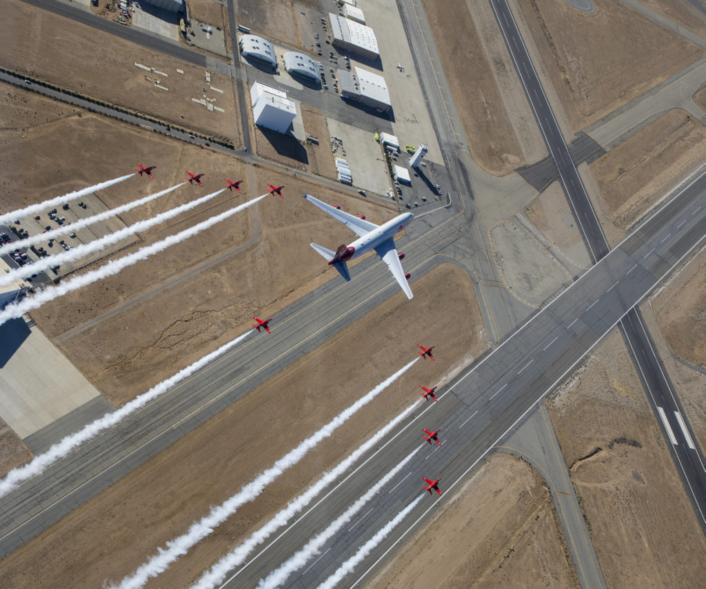 Pictured is the Virgin Orbit 'Cosmic Girl' launch aircraft flying in formation alongside the Red Arrows Hawk jets. (© Crown Copyright 2019)