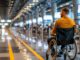 Man in wheelchair waiting at a busy airport terminal,
