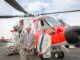 Barnbrook systems managing director Tony Barnett (L) and Sir Donald Spiers, then chairman of Farnborough Aerospace Consortium (R) at the 2018 Farnborough International Airshow in front of a helicopter with Barnbrook System's fuel switch