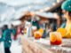 Guests unwind at a cozy outdoor bar in a ski resort, savoring colorful cocktails while snow gently falls around them, creating a festive winter atmosphere.