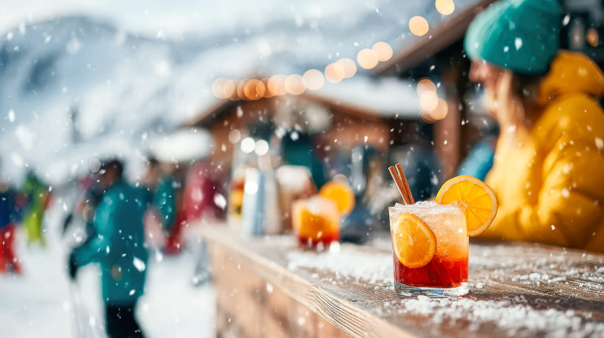 Guests unwind at a cozy outdoor bar in a ski resort, savoring colorful cocktails while snow gently falls around them, creating a festive winter atmosphere.